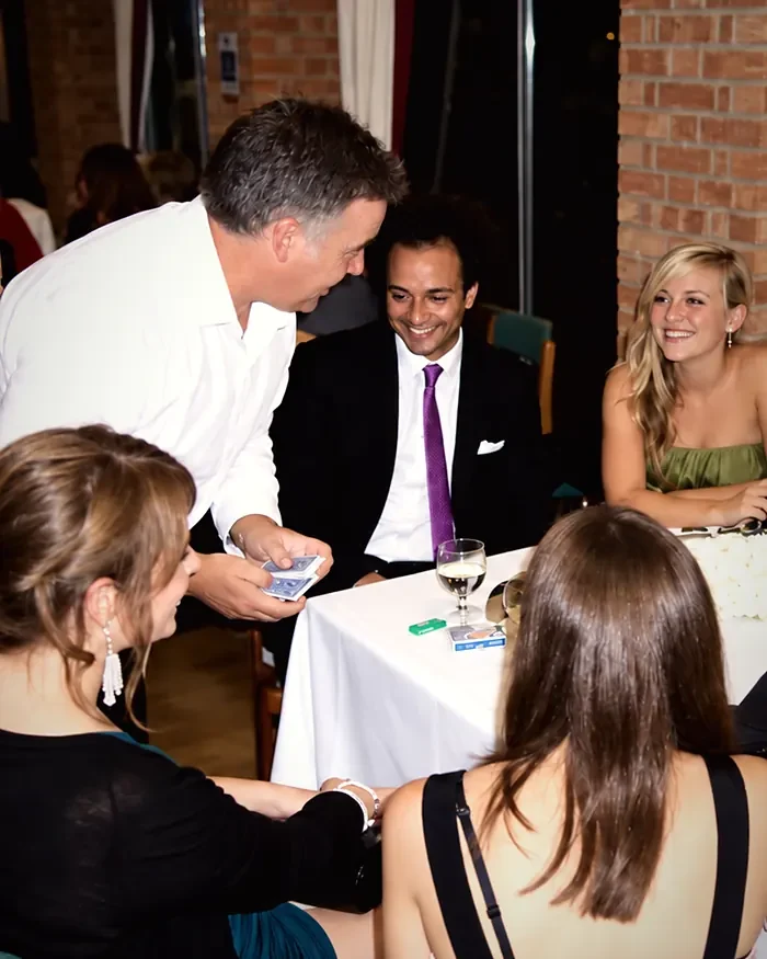 Jonathon performing close-up card magic for guests seated around a table