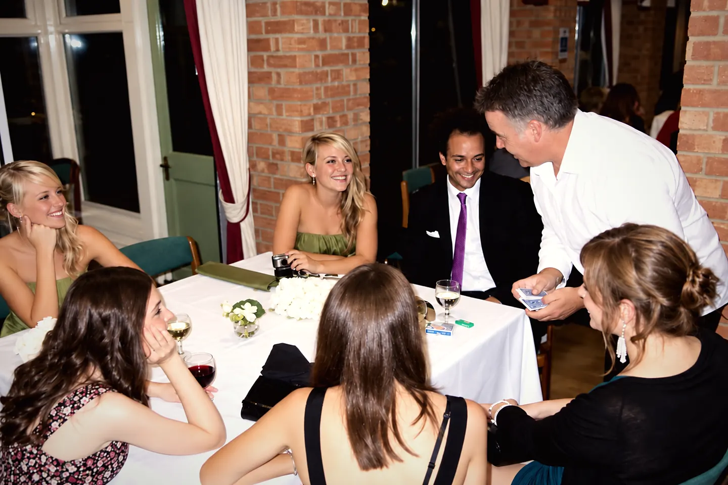 Jonathon performing close-up card magic for guests around a candlelit dinner table